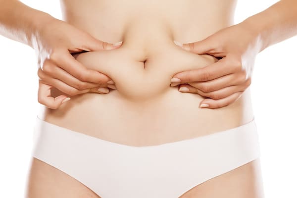 Woman pinching stomach skin/fat around belly button