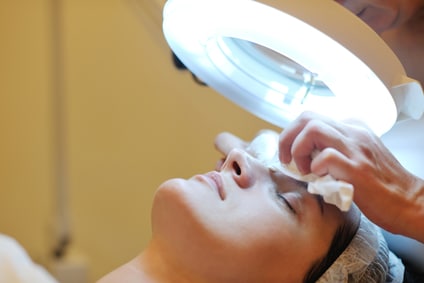 Female patient getting facial with bright circular light shining on face