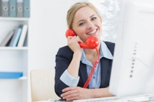 stockfresh 2917395 smiling female executive using red land line phone at desk sizeS