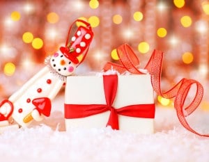 Holiday background with cute snowman Christmas tree decorative ornament & gift box in snow over abstract defocus lights