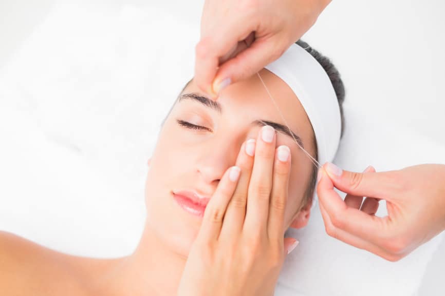 Close up of a hands threading woman's upper eyes