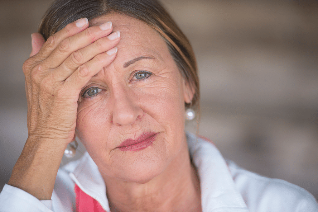 Older woman with wrinkles with hand on forehead