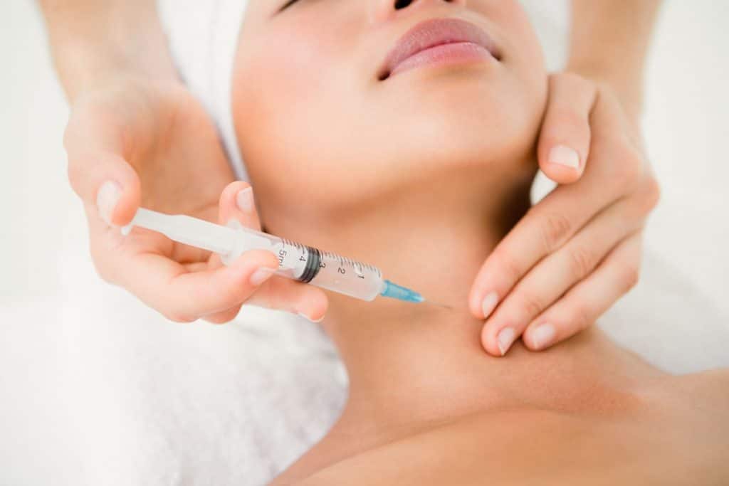 Nurse injecting fluid into woman's neck