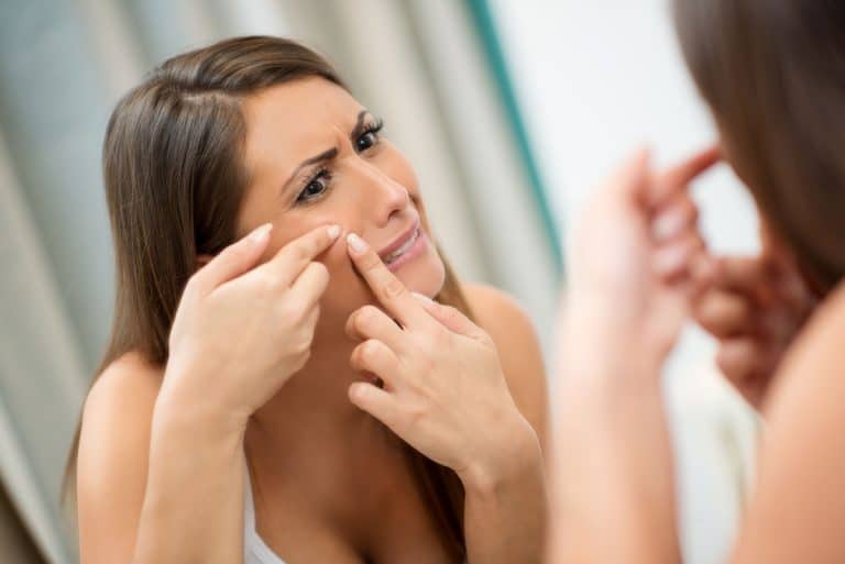 Woman looking in mirror with acne