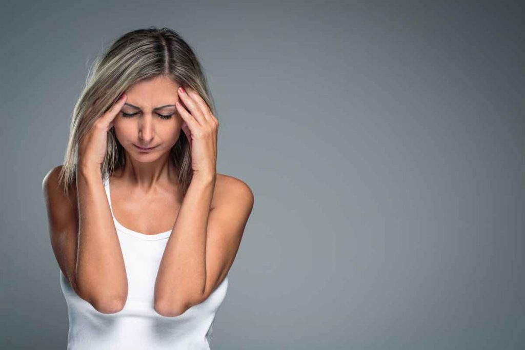 Young woman holding her head, frowning in pain