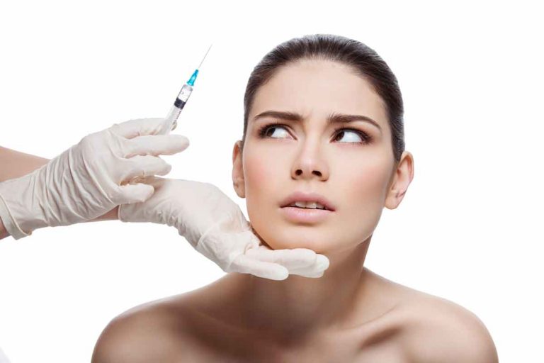 Brunette woman looking side eyed at physician with syringe in gloved hand