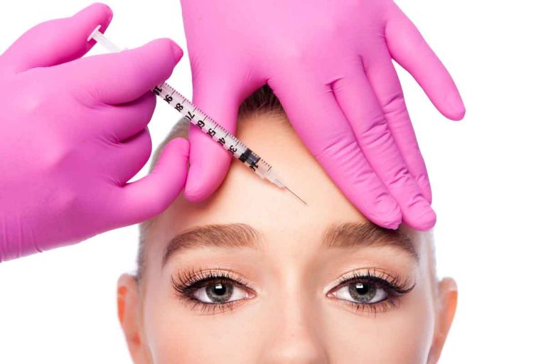 Woman about to have injection in forehead by nurse with pink gloves