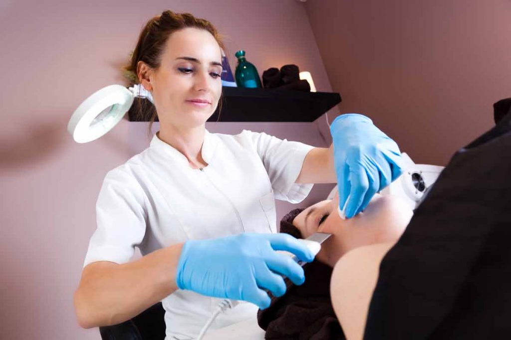 Nurse preforming procedure on woman's face in spa type setting