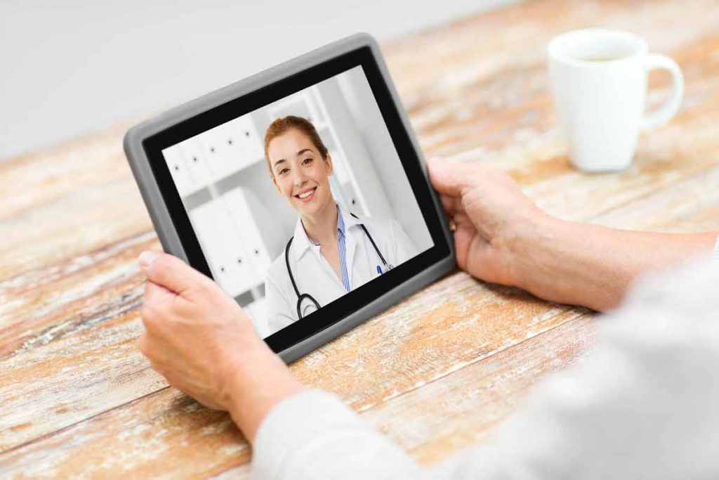 Physician sitting at desk doing face-to-face meeting on notebook