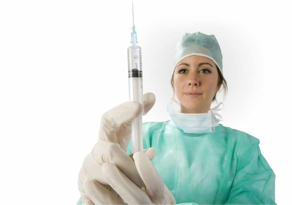 Doctor in green surgical scrubs with syringe in gloved hands