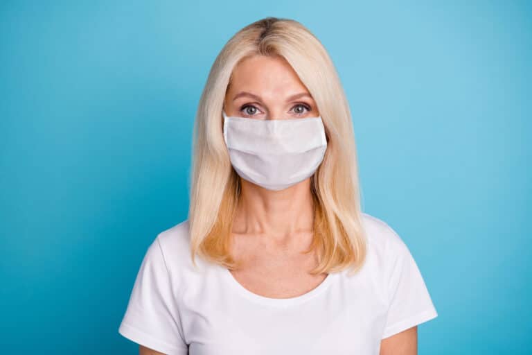 Blonde woman wearing COVID-19 mask in white t-shirt and turquoise background