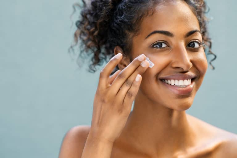 Young black woman smiling putting on face cream