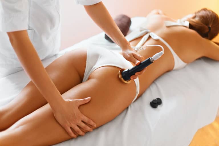 Woman laying on stomach in white bikini getting Body Contouring Treatments